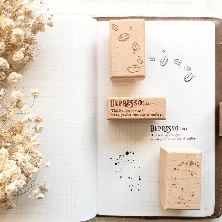 Rustic Roast wooden stamps with coffee designs on an open notebook with dried flowers