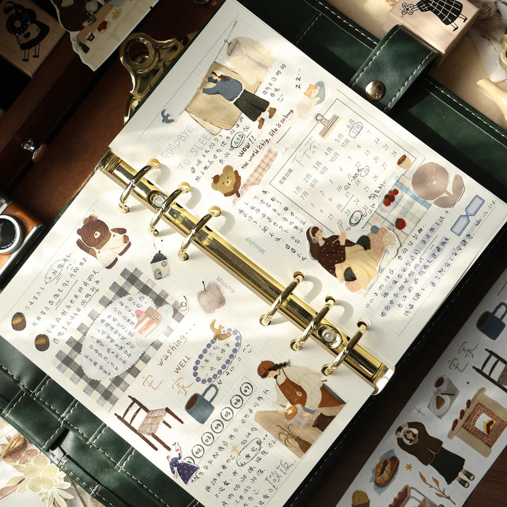 Gold ring-bound planner decorated with Salty Lifestyle PET Tape stickers on a wooden surface