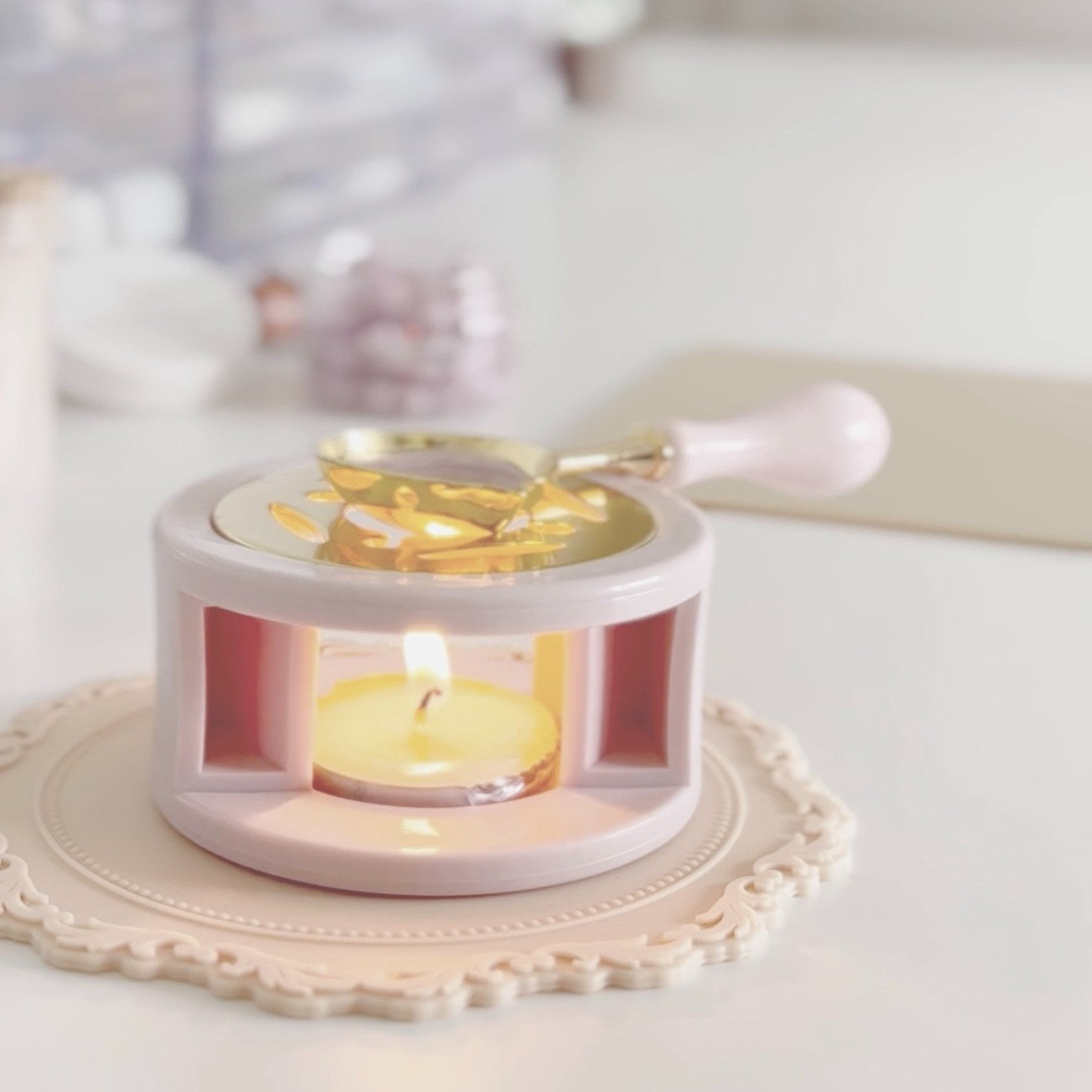 Candle warmer with a lit candle inside on a decorative plate.