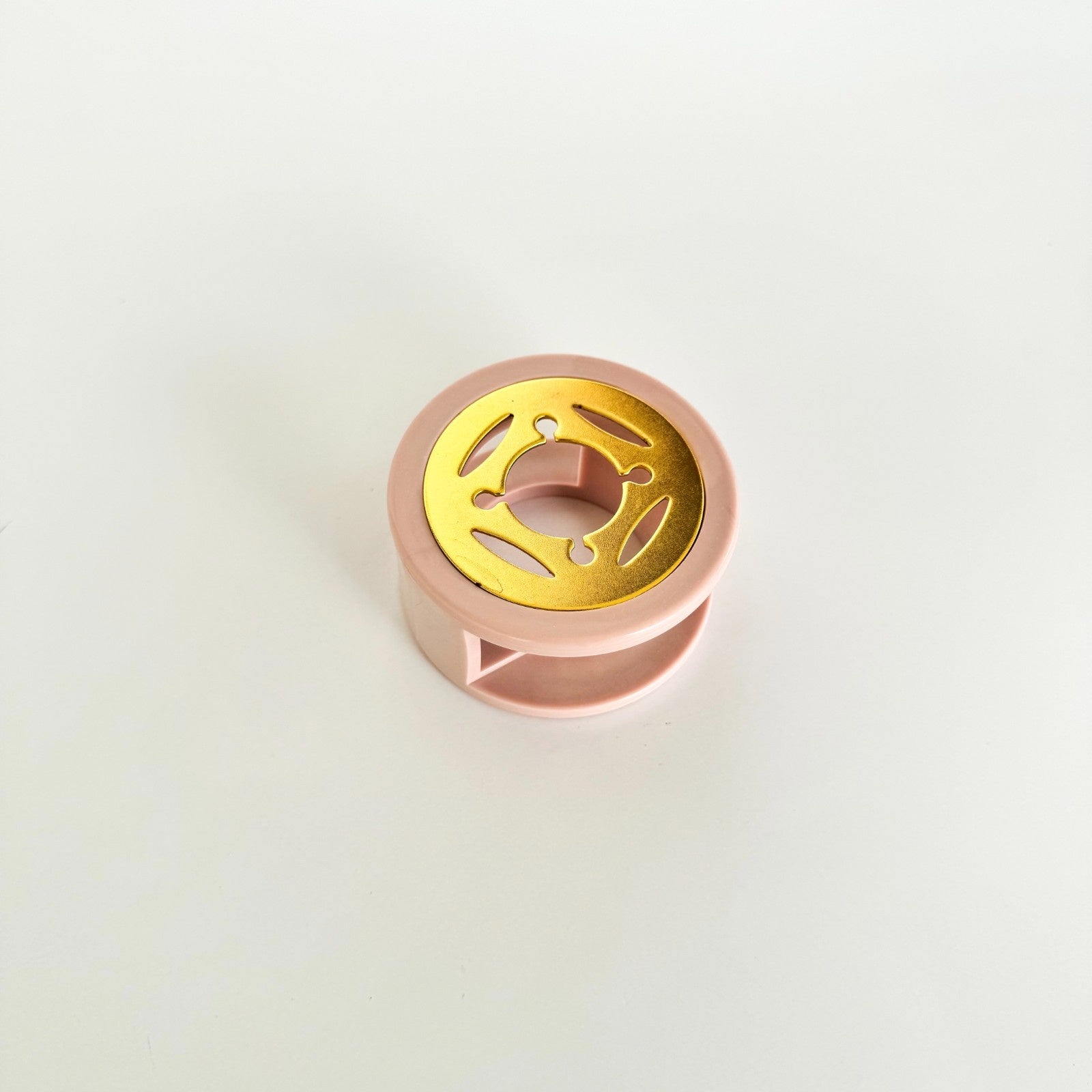 Rose gold and gold metal component on a light gray background