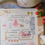 Notebook with tea-themed illustrations and text on a wooden surface