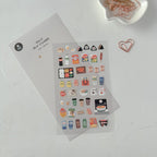 Sticker sheet with various small icons on a white surface with paper clips.