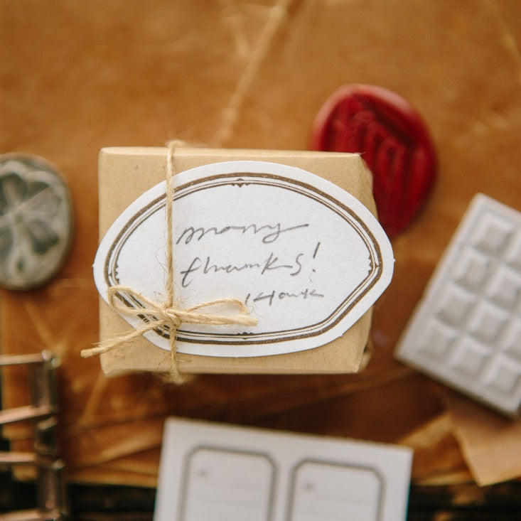 Small wrapped gift tagged with a Shell Label Letterpress many thanks card on texture