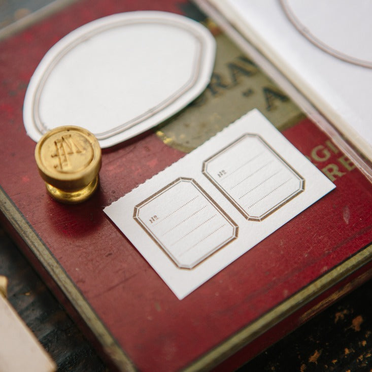 Shell Label Letterpress Memo Pad with gold stamp detail and stationery on a wooden surface