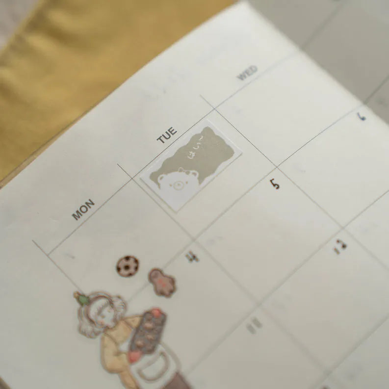 Calendar decorated with Kuma Label Sticker Tape bear stickers on a white surface, top view