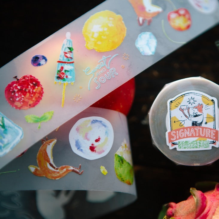 Colorful stickers on a transparent sheet with a 'Signature' sticker on a dark surface.