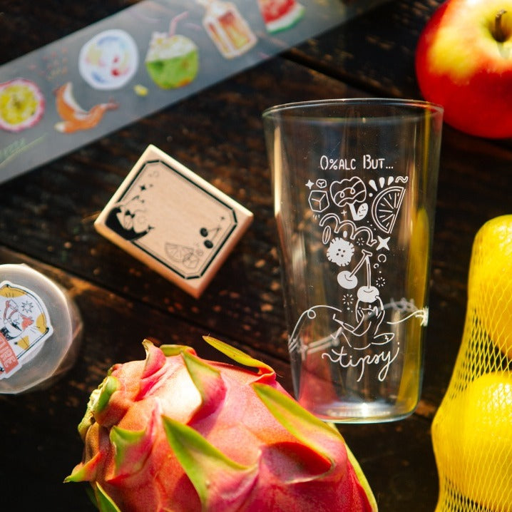Clear glass with engraved design on a wooden surface with dragon fruit and apple.