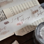 Notebook with handwritten text and a jar on a wooden surface