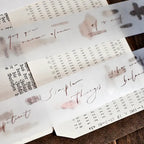 Translucent sheets with floral designs and text on a wooden surface