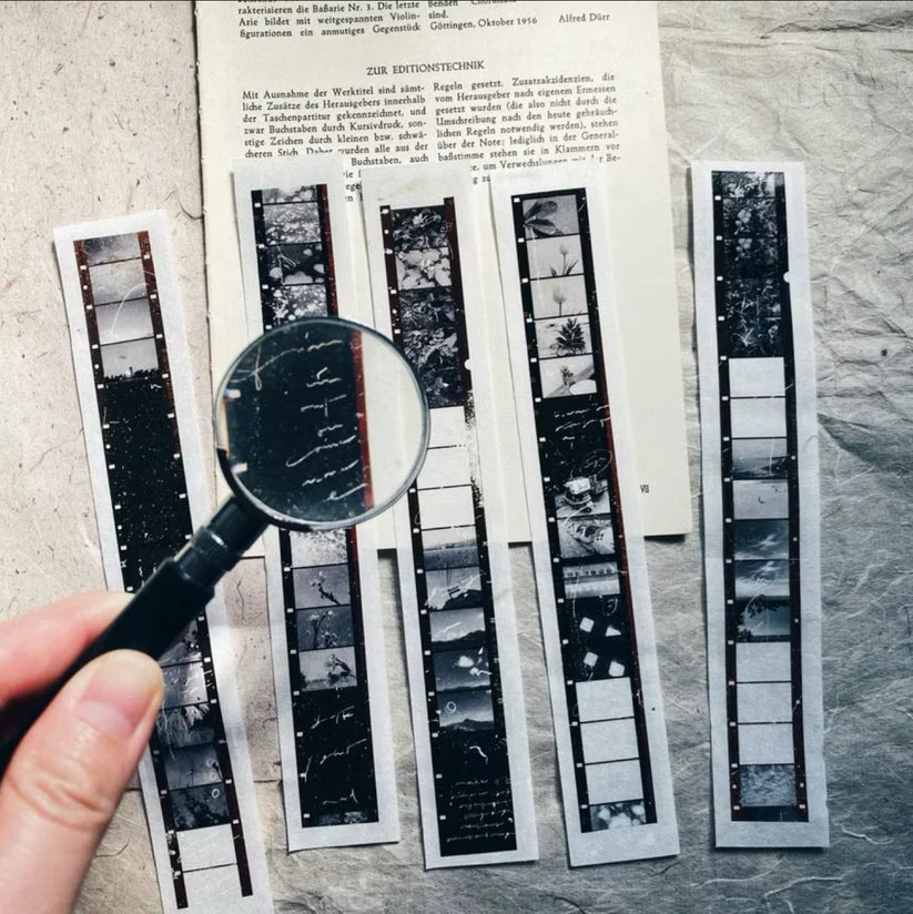 Skyline PET Tape film negative strips viewed through a magnifying glass on a textured surface