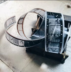 Film reel with black and white film strip on a wooden surface