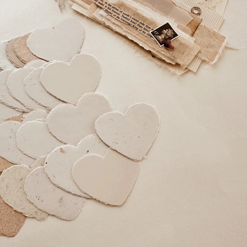 Small Heart Handmade Paper hearts with a stack of papers in the soft background, styled detail view