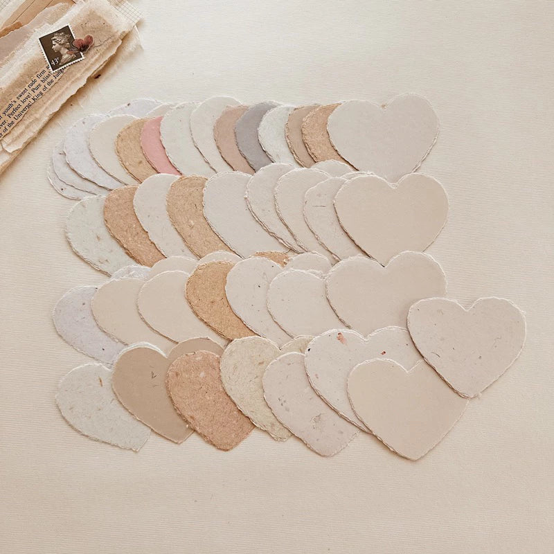 Small Heart Handmade Paper cutouts in mixed pastel shades on a textured surface, styled detail view