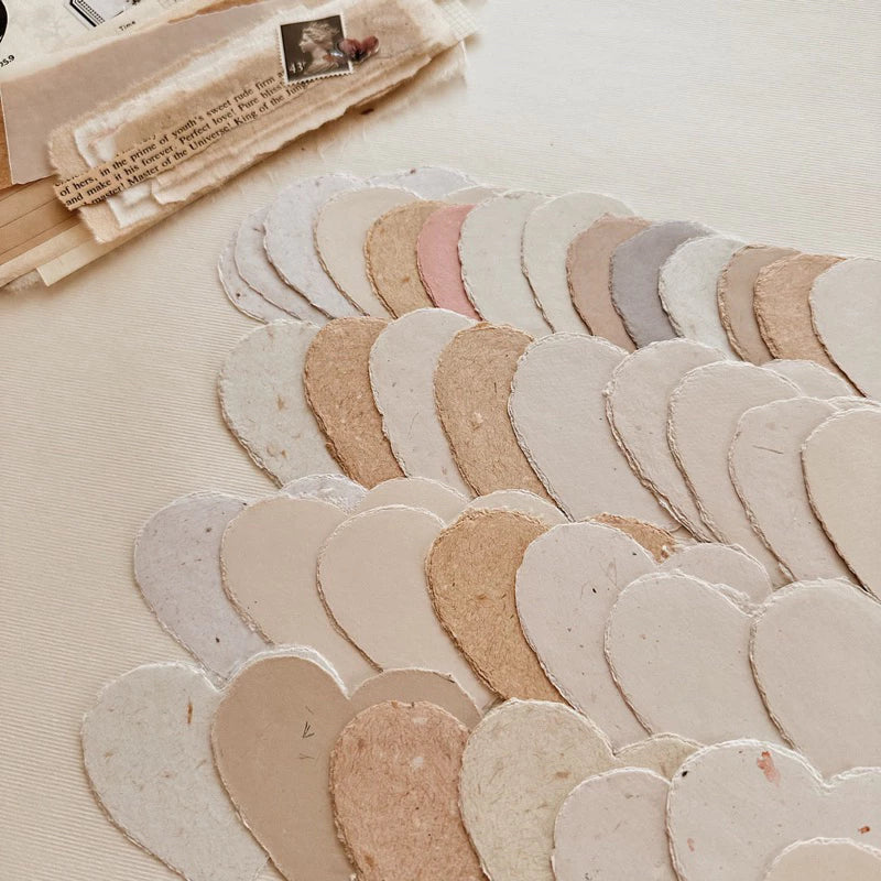 Small Heart Handmade Paper cutouts in earthy tones arranged on a textured surface