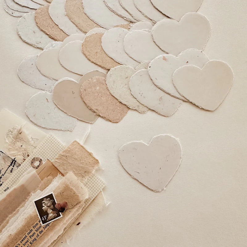 Heart-shaped ceramic pieces arranged on a textured surface with a vintage book and photo.