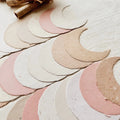 Set of crescent moon-shaped paper cutouts in various colors on a light wooden surface.
