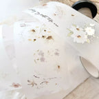 White mug with floral design and text on a light wooden surface