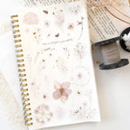 Spiral-bound notebook with floral stickers on a white surface