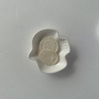 White ceramic dish with a decorative emblem on a gray background