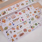 Set of decorative washi tape rolls with food illustrations on a wooden surface.