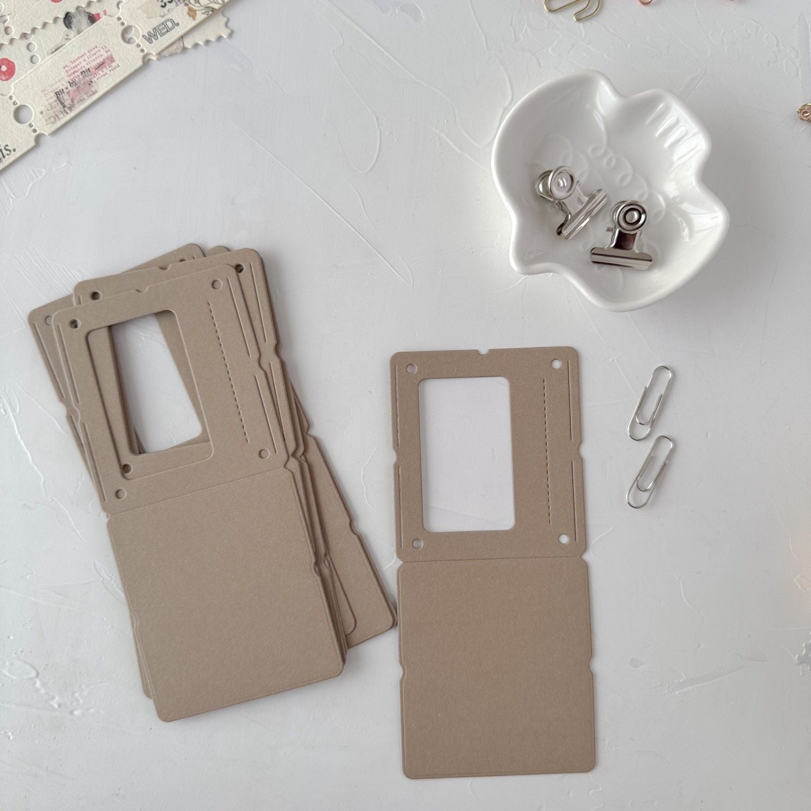 Two beige metal frames on a white surface with small clips.