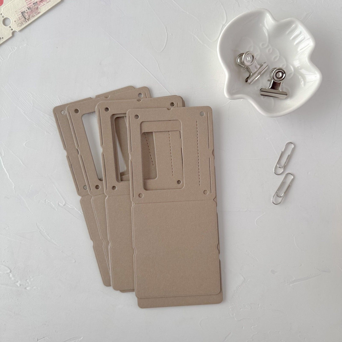 Three coffee Specimen Card Vol. 1 tag cards with a paper clip on a light grey background