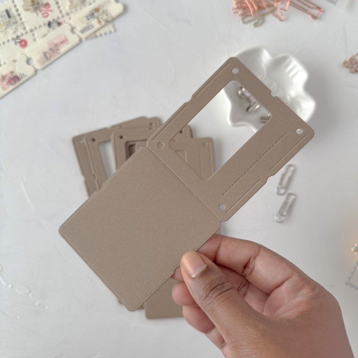 Hand holding a coffee Specimen Card Vol. 1 card with cutout shapes on light grey