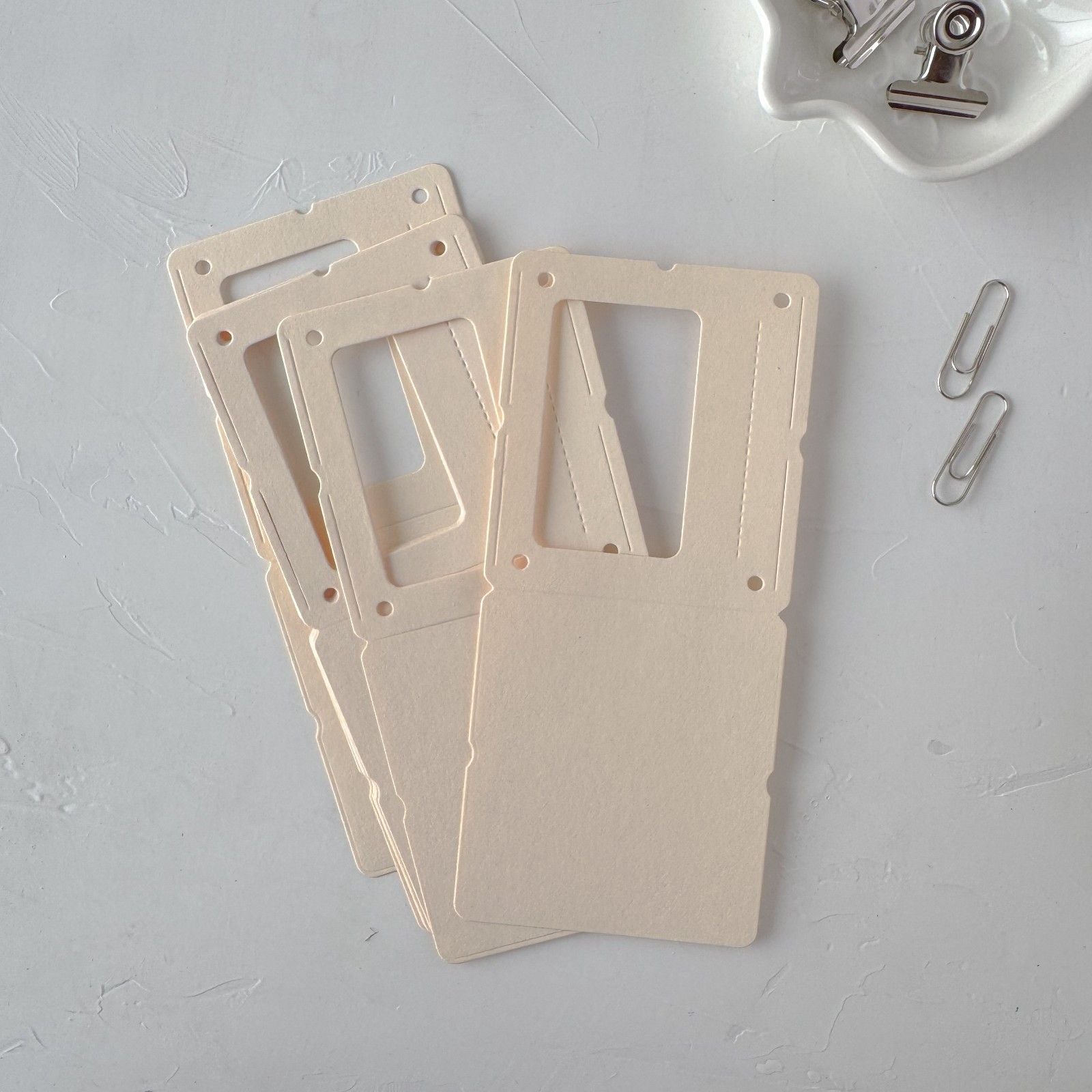 Three beige plastic card holders on a gray surface with paper clips.