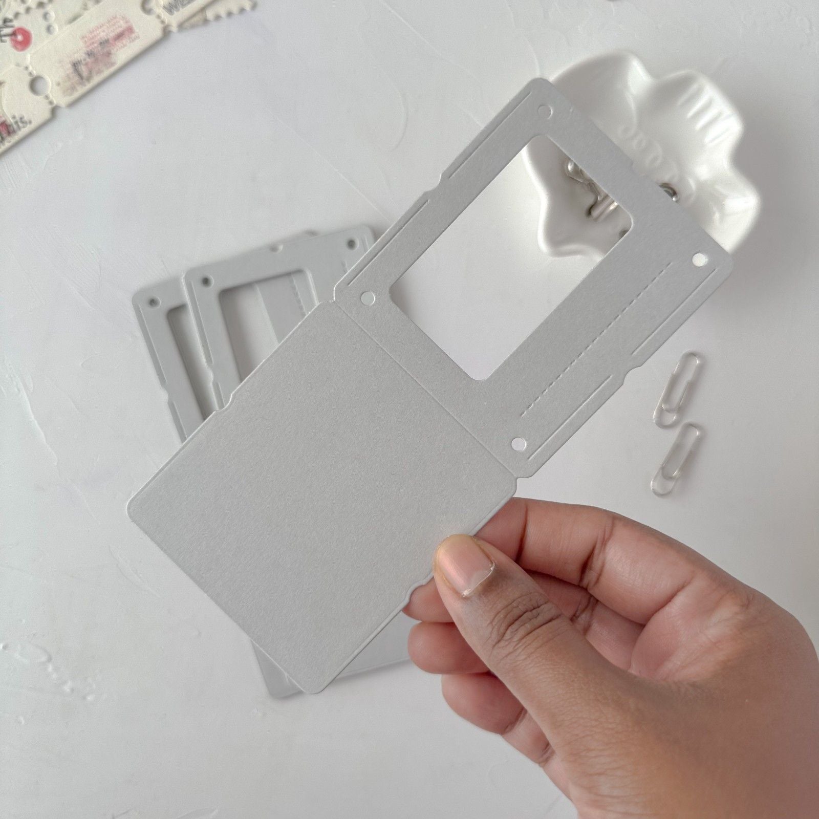 Hand holding a gray plastic component with a white background