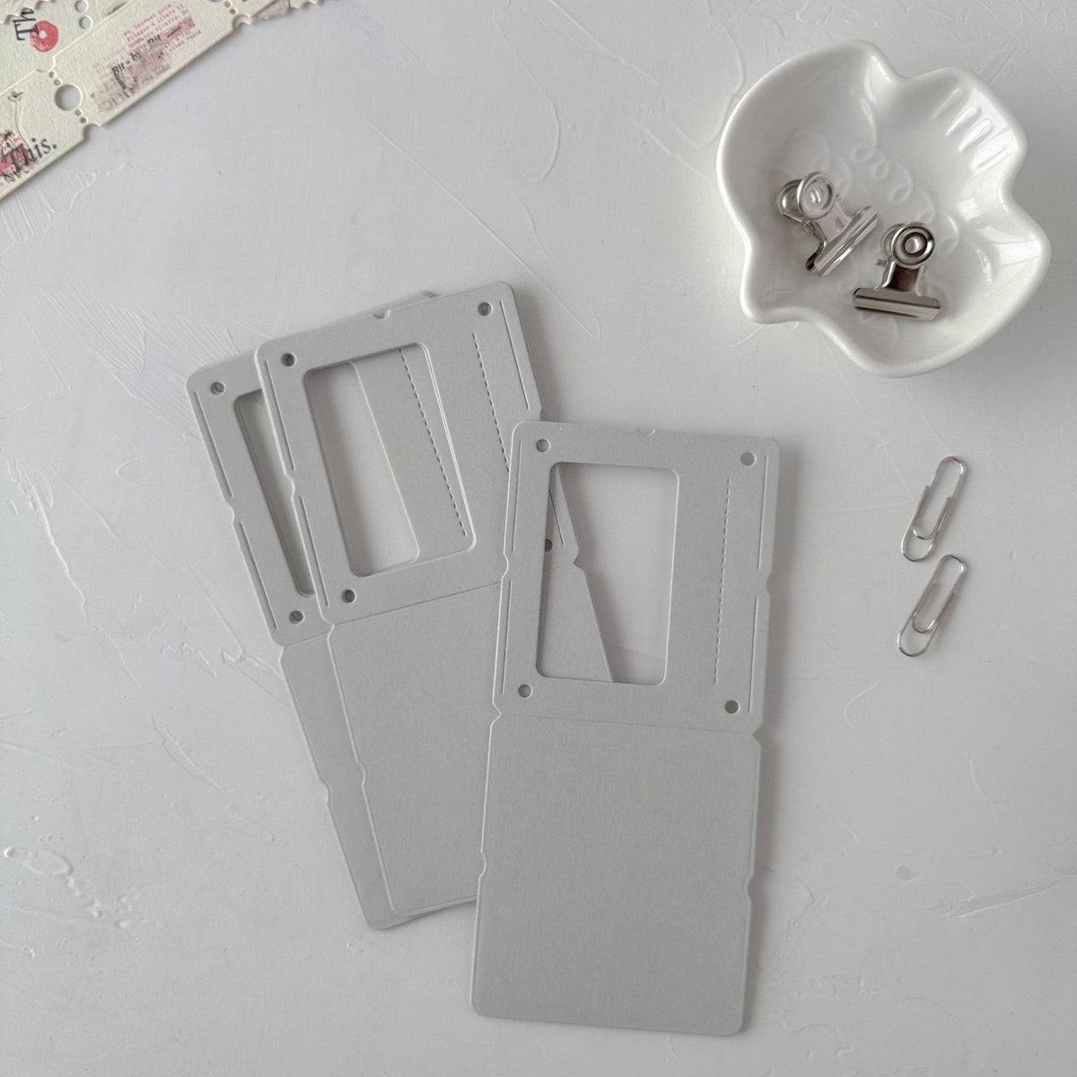 A trio of grey Specimen Card Vol. 1 cards on a white surface with small metal clips