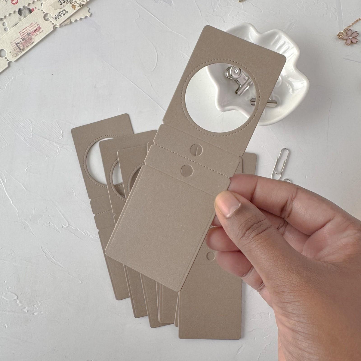 Hand holding coffee-toned Specimen Card Vol. 2 display cards on a light grey background