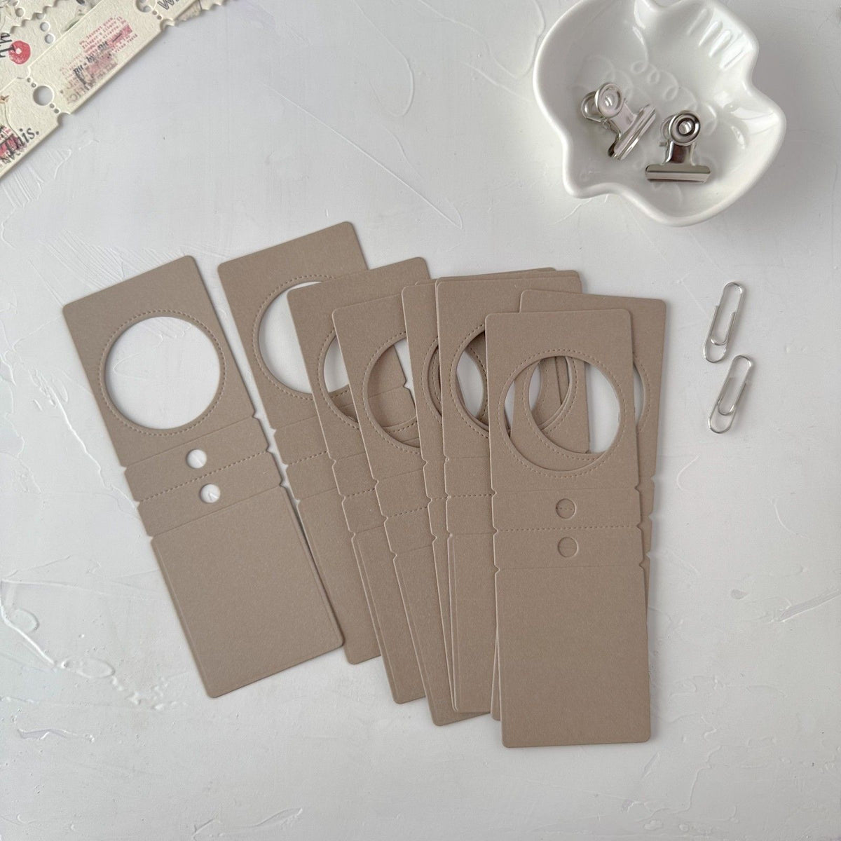 Set of deep coffee Specimen Card Vol. 2 cards with clips on a light grey surface