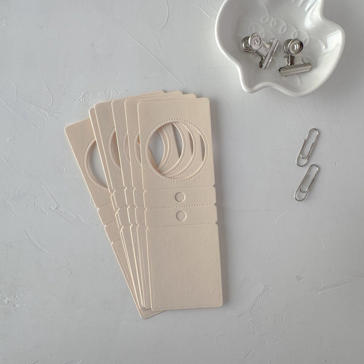 Cream Specimen Card Vol. 2 cutout card with small clips on a grey surface, styled detail view