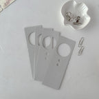 Gray door hangers with circular cutouts on a light gray surface.