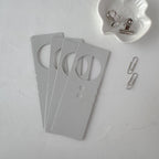 Set of gray door hangers with circular cutouts on a light gray surface.
