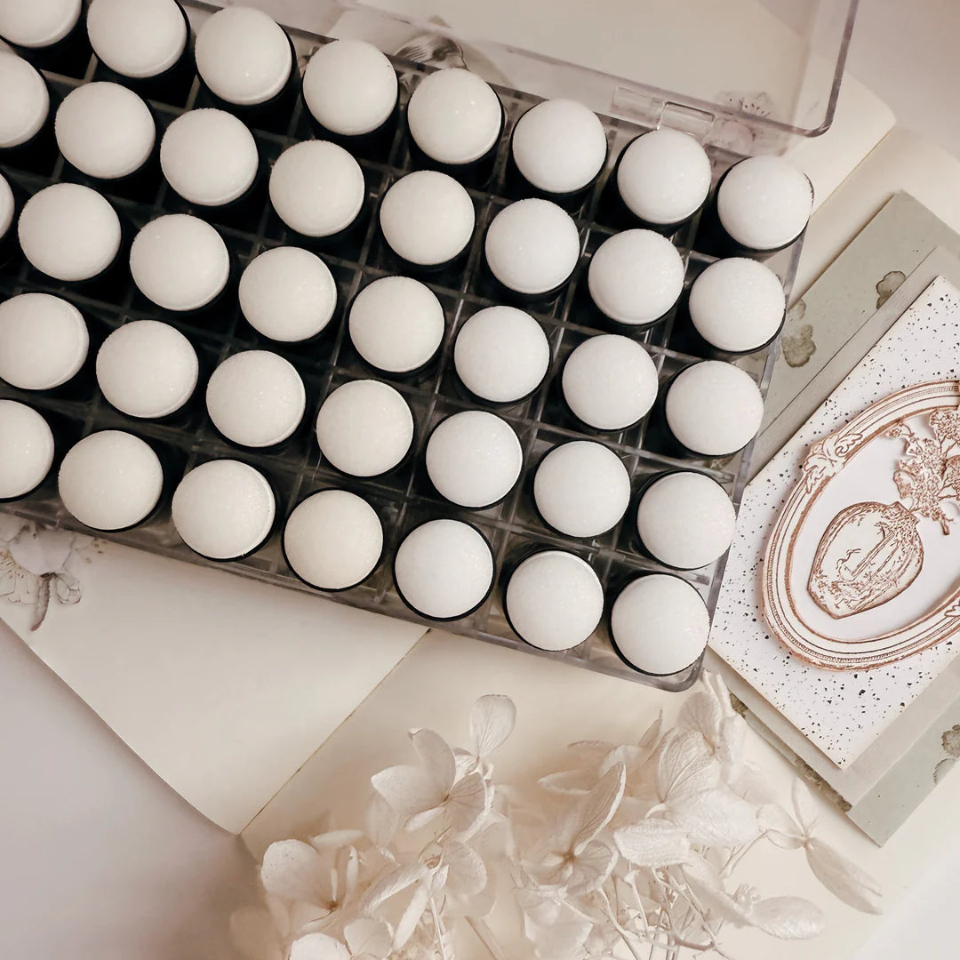 Set of white makeup items in a case with a decorative box on a light background