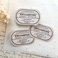 Vintage-style Brillanté labels on a textured surface with dried flowers.