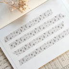 Set of floral washi tape strips on a notebook page with dried flowers.