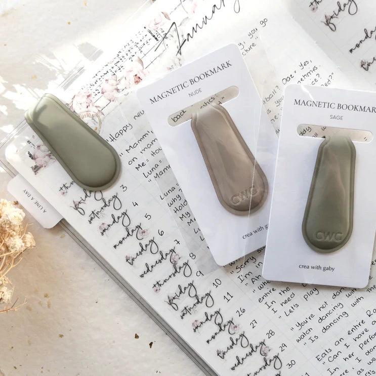 Two Spring Cottage Magnetic Bookmarks in packaging resting on a decorated notebook page