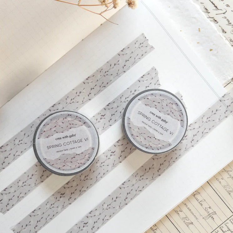 Two Spring Cottage VI Washi Tape containers on a textured surface with a book and dried flowers