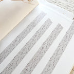 Decorative paper with gray speckled pattern on a white surface