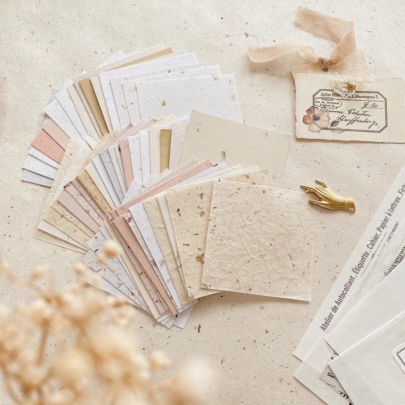 Square Paper Vol. 1 sheets in varied sizes styled with a decorative ribbon on texture