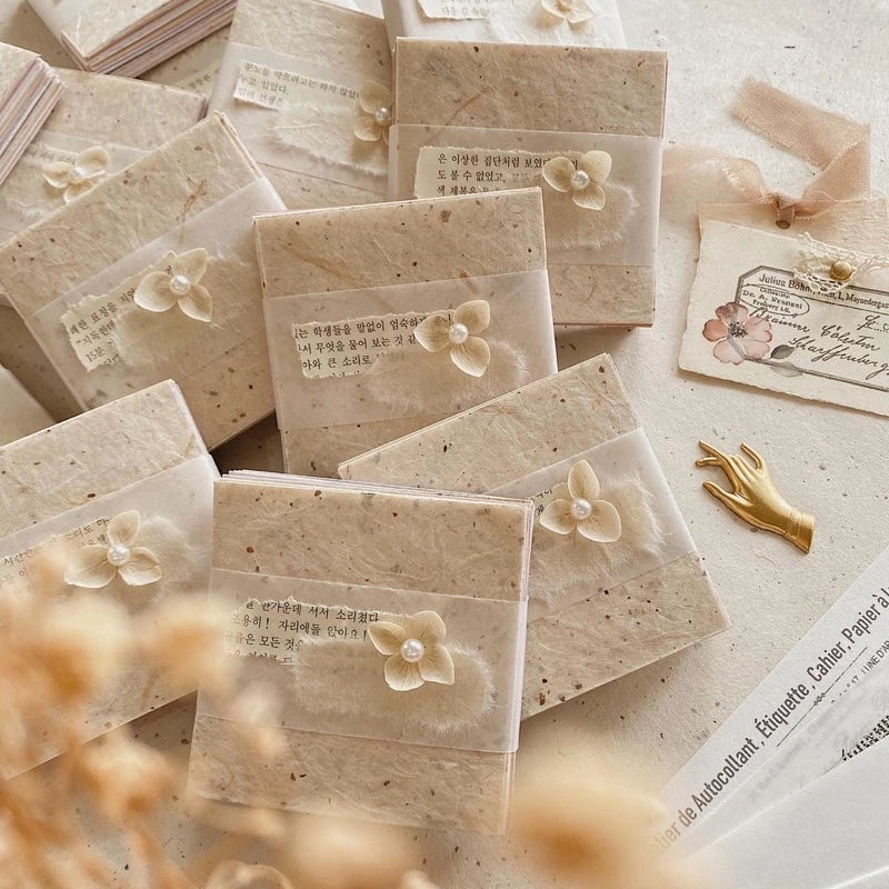 Square Paper Vol. 1 sheets styled as envelopes with floral embellishments on texture