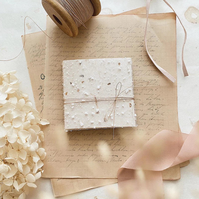 Small wrapped gift styled on Square Paper Vol. 2 vintage sheets with ribbons and flowers