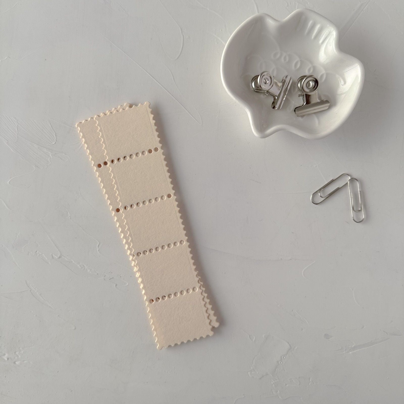 Cream Stamp Card Vol. 1 perforated strip with a clip container on a grey studio surface