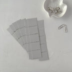 Gray grid stickers on a white surface with a paper clip and binder clip.