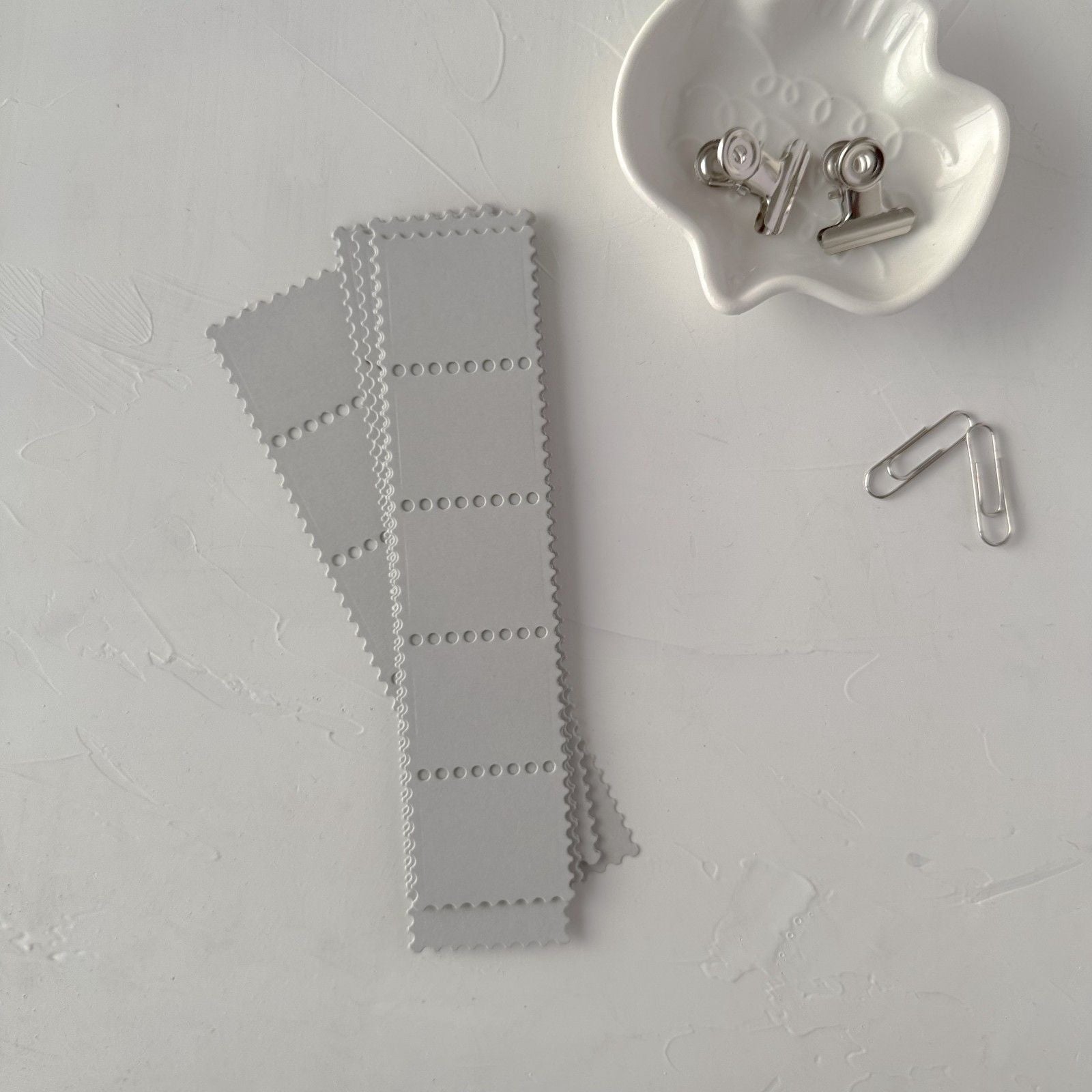 Grey Stamp Card Vol. 1 cards on light grey with a small white dish and metal clip
