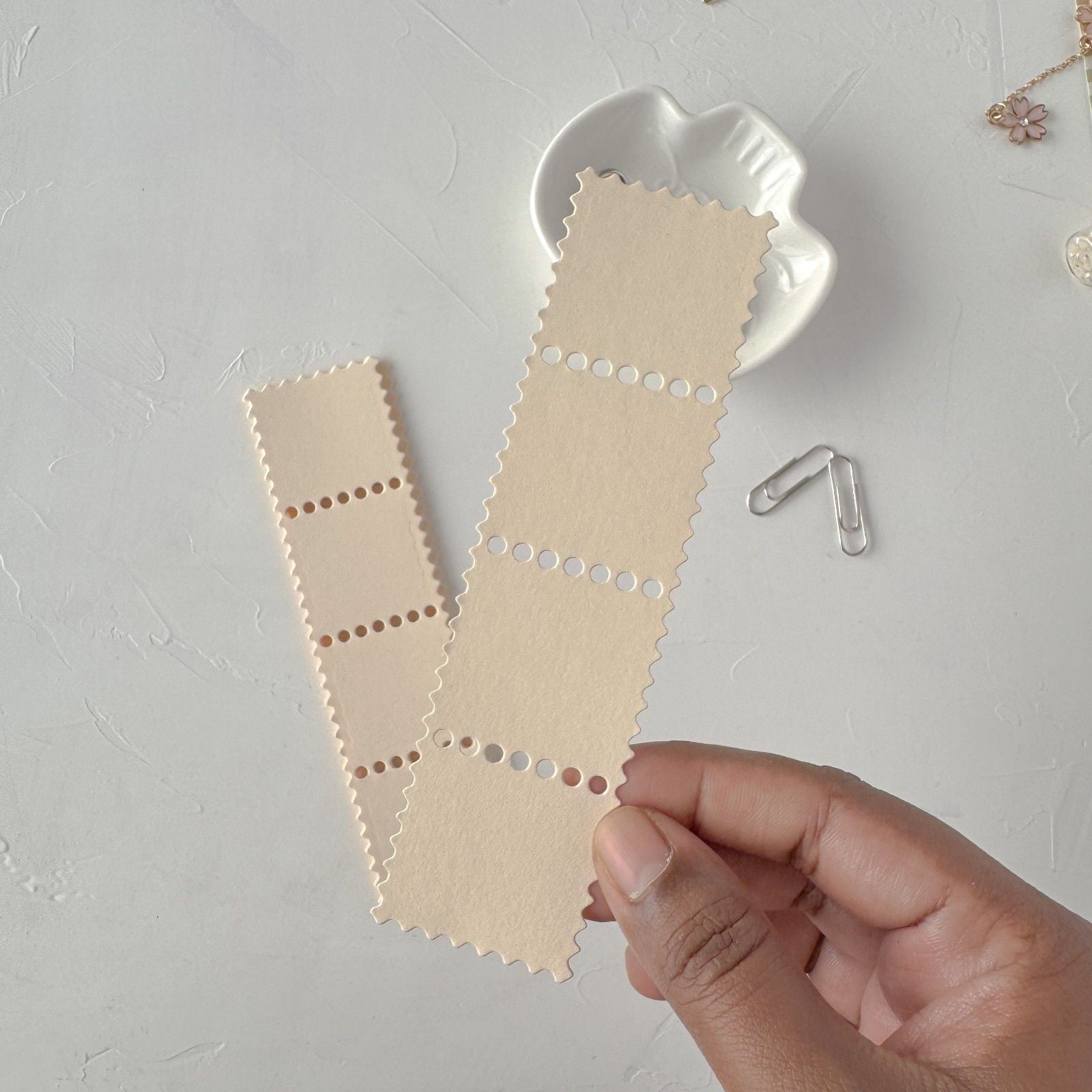 Hand holding cream Stamp Card Vol. 2 cards with a white heart-shaped dish on light grey