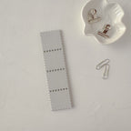 Small fabric swatch with metal clips on a textured white surface