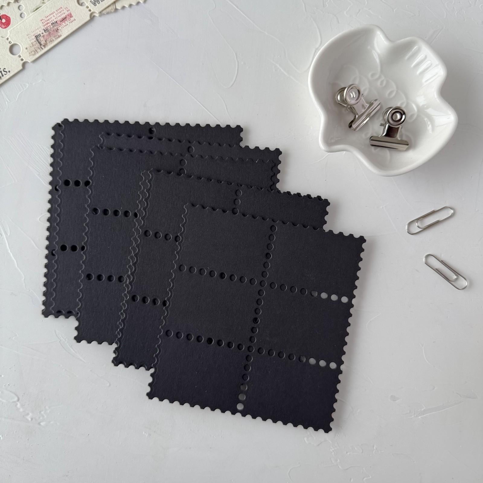Black woven placemats on a white surface with a paper clip and small container.